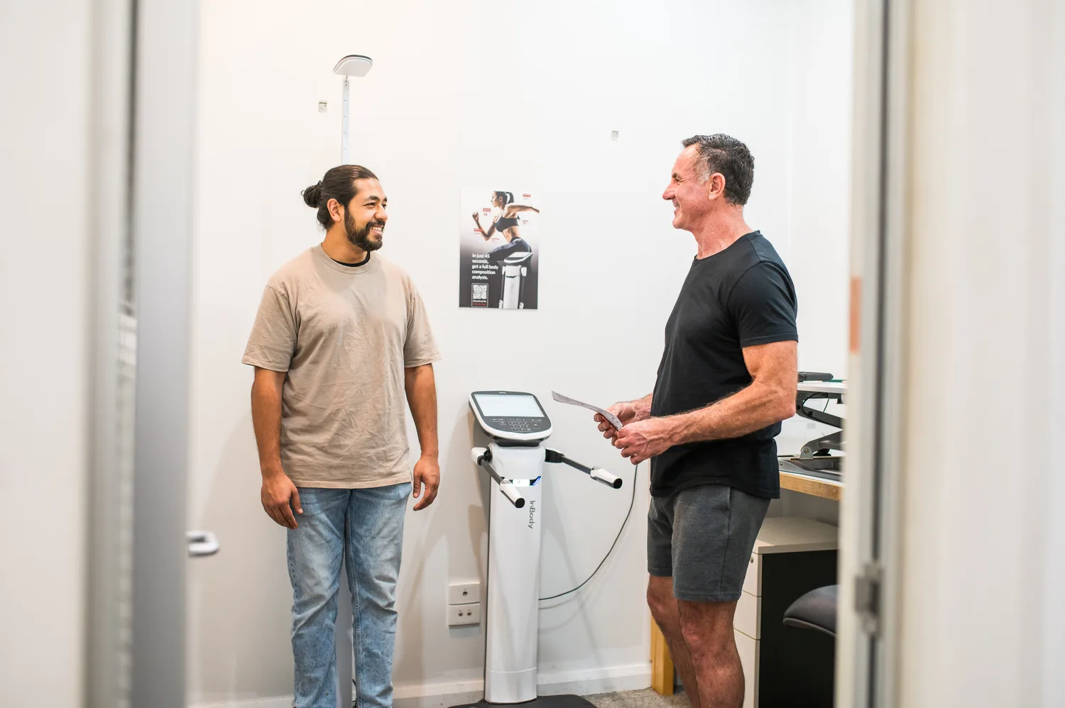 Nate and a client talking beside the body composition scanner at the Supercell Hub