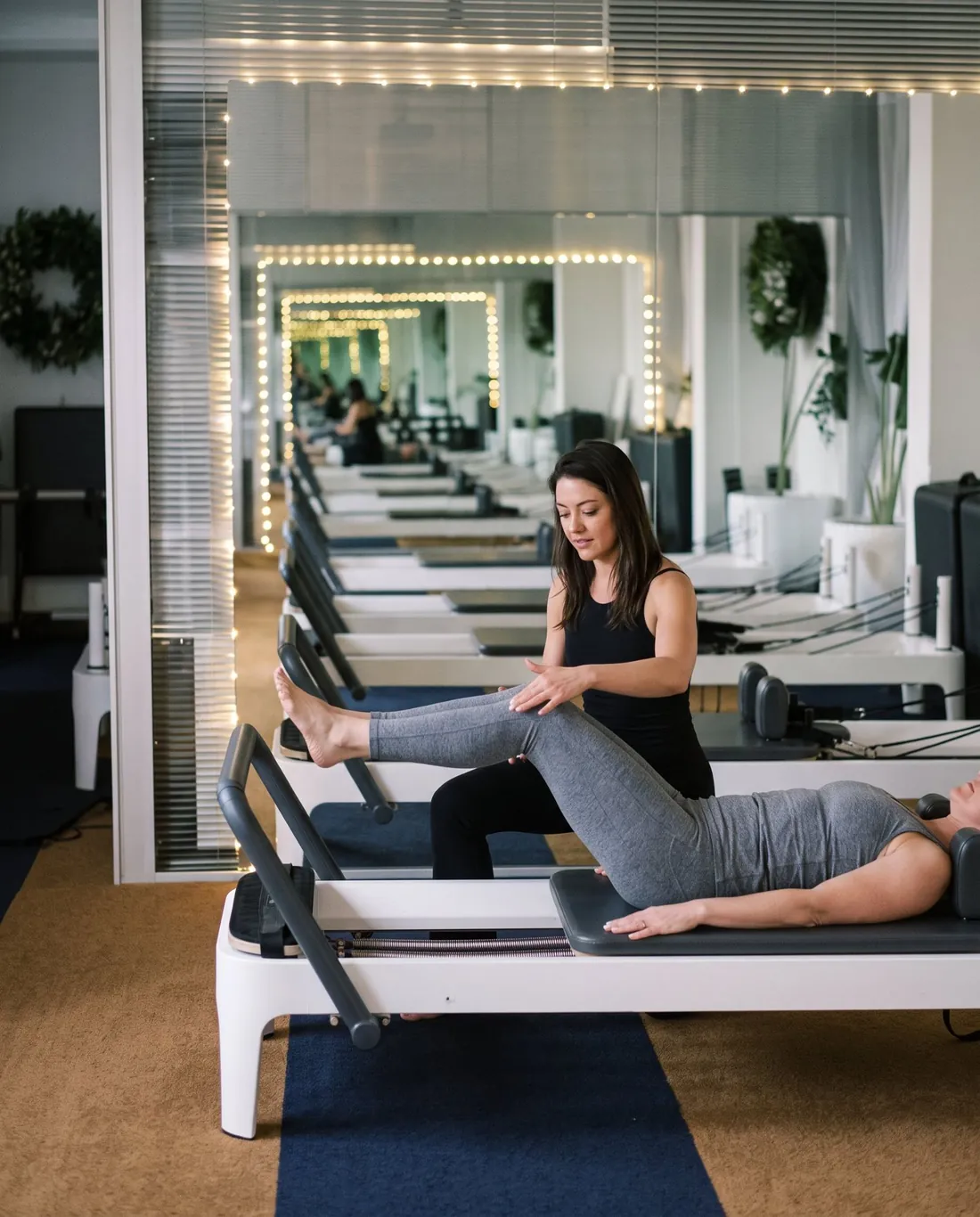Galina guiding a client through a supported leg exercise on the reformer.