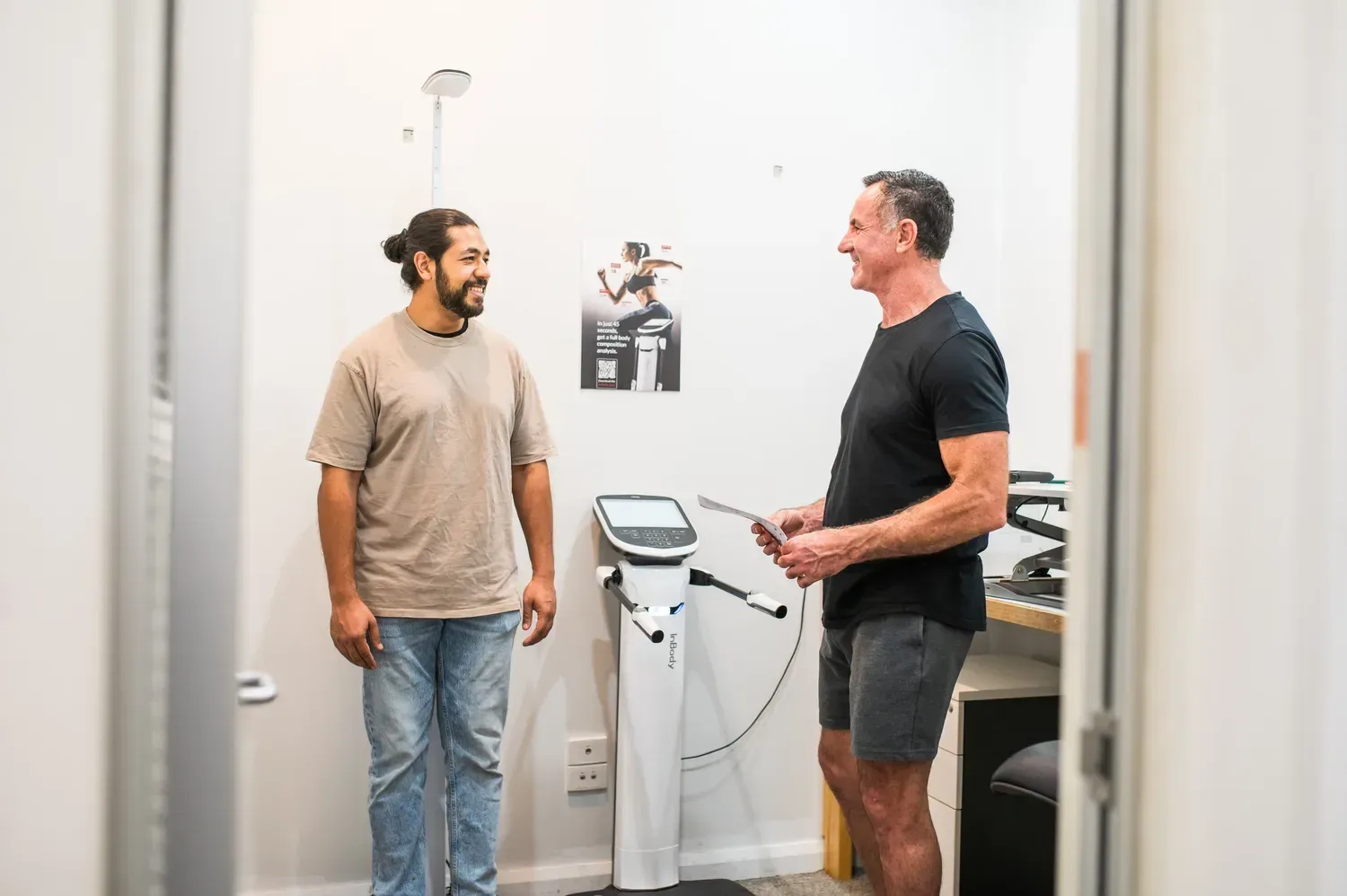 Nate and a client talking beside a body composition scanner at the Supercell Hub.